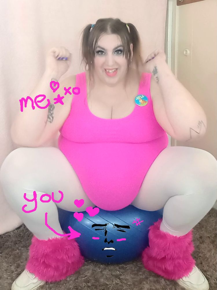 A large bodied woman in exercise gear sitting on an exercise ball with an anime meme face on it. Suggesting that the large woman is sitting on a person and the person is enjoying it, albeit an effort.