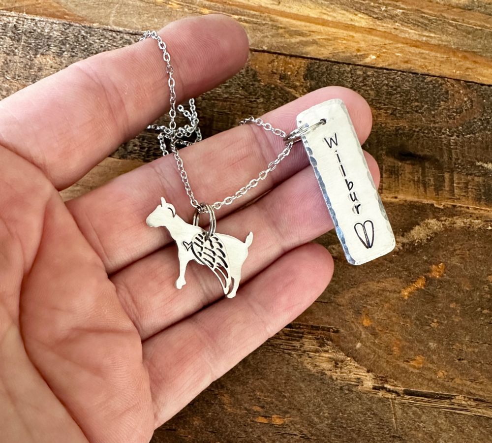 Necklace with goat pendant and angel wing and a personalized name charm with Wilbur and a goat hoof print stamped on it
