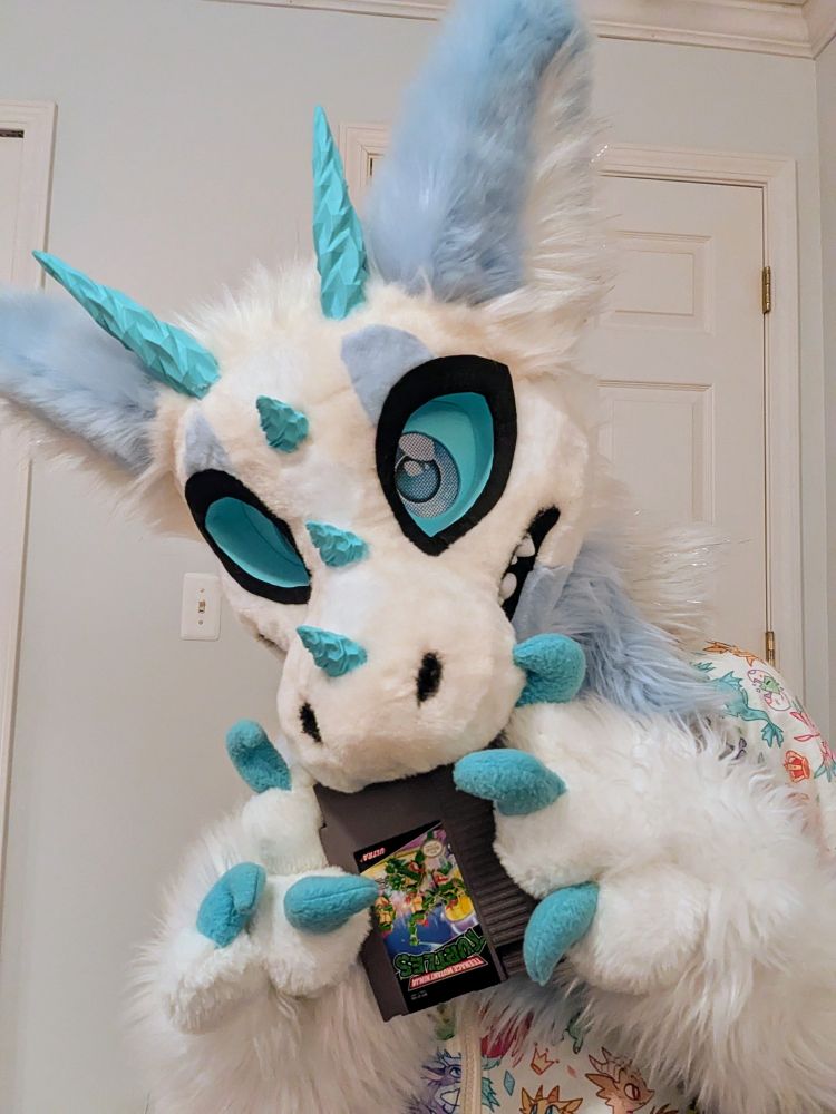 Ice Dragon Fursuiter blowing into a game cartridge for the Nintendo Entertainment System (NES)