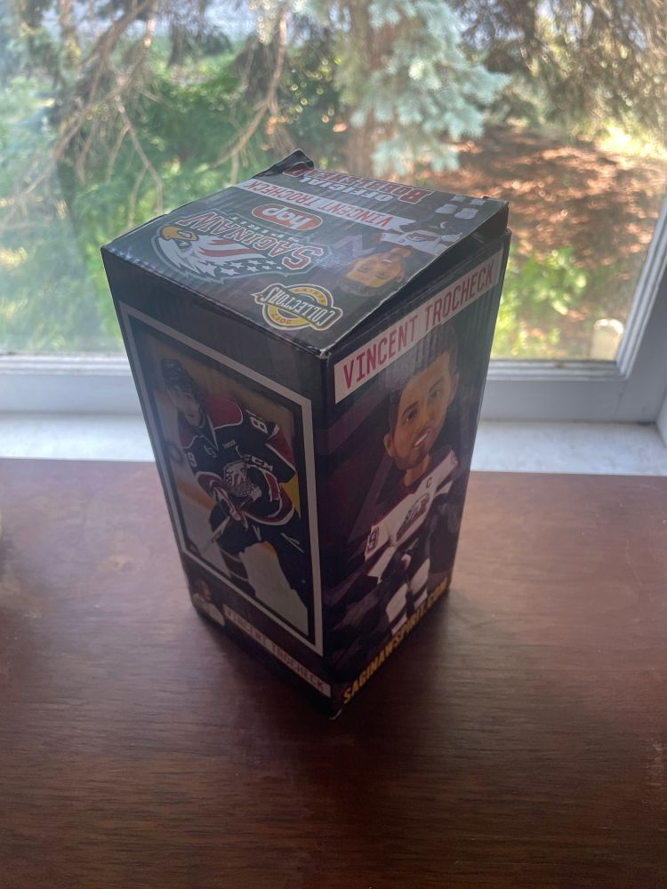 a Saginaw Spirit Vincent Trochek bobble head box showing the bobble head on one side and a photo of Trochek on the ice in his Spirit jersey on the other visible side 