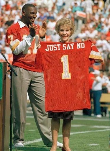Nancy Reagan standing next to Doug Williams, holding a 1 jersey that reads JUST SAY NO