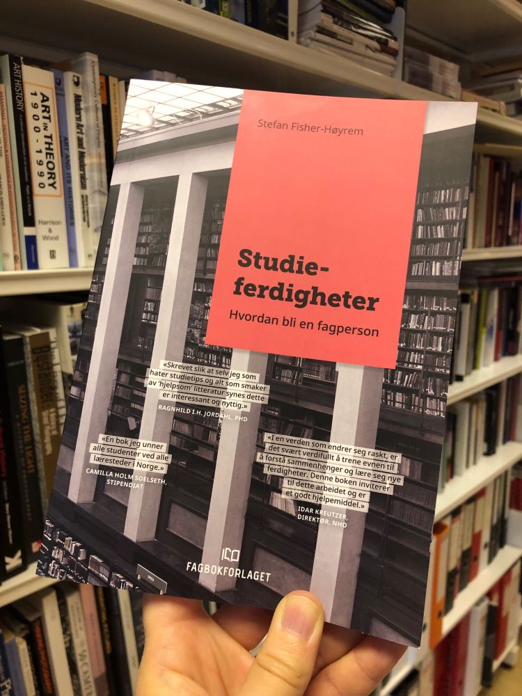 Omslaget til boken Studieferdigheter. Hvordan bli en fagperson av Stefan Fisher-Høyrem vises mot en bakgrunn av bokhyller fylt med bøker.