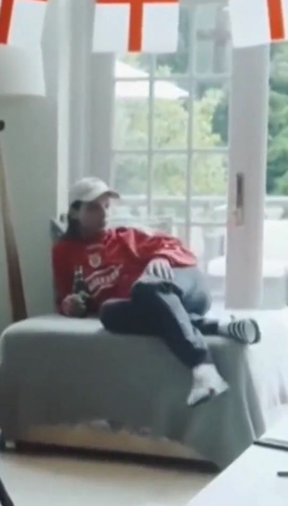 Long haired sits on a piece of furniture in a lounging position with his legs crossed 