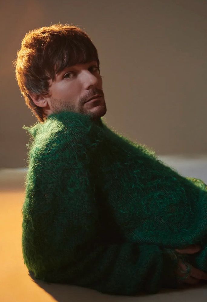 Louis looks to camera in the Dork green fuzzy sweater, with glow in the light 