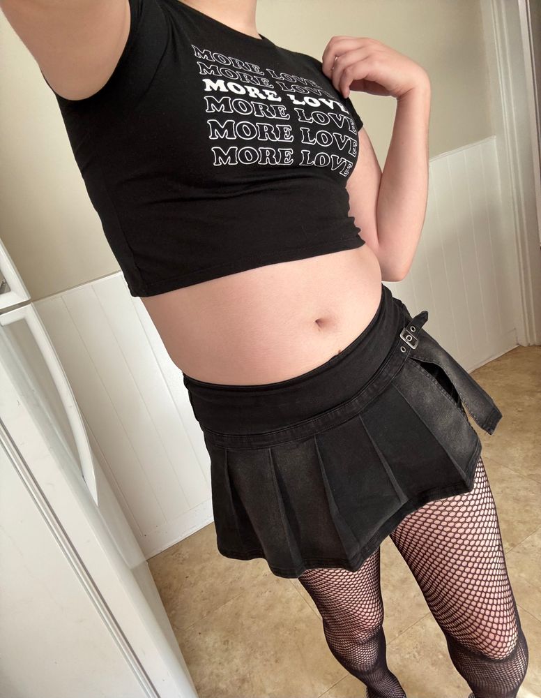 a selfie of the rest of the outfit, a crop top, a faded black skort and fishnets