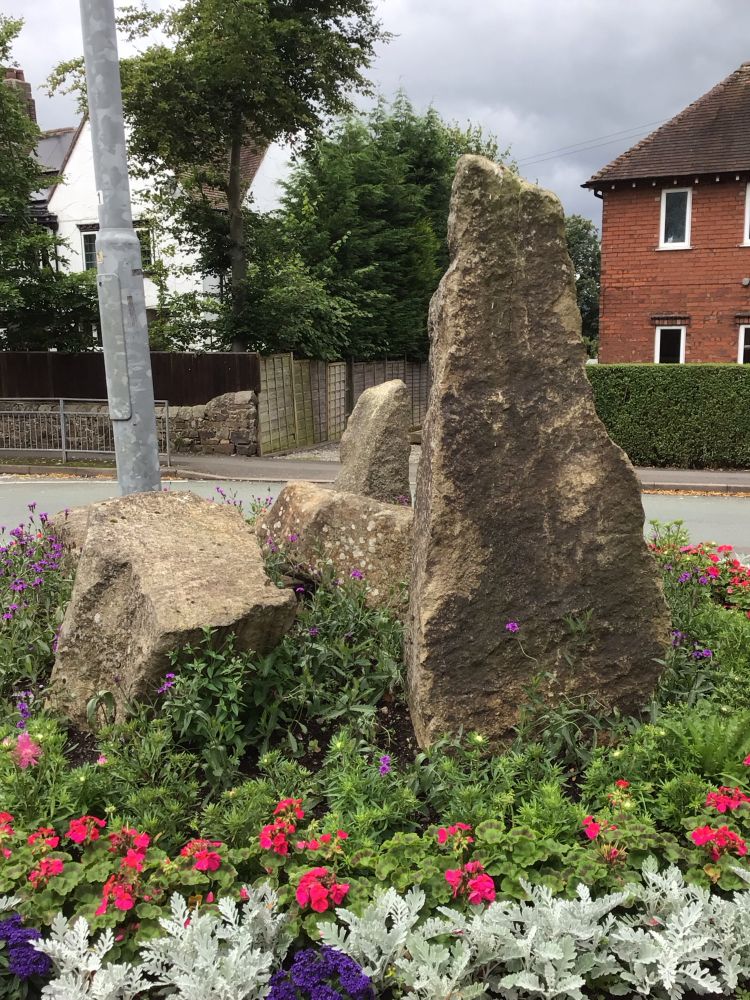 Colour image of a modern stone circle on a road traffic island in Leek. Surrounded by decorative plants.