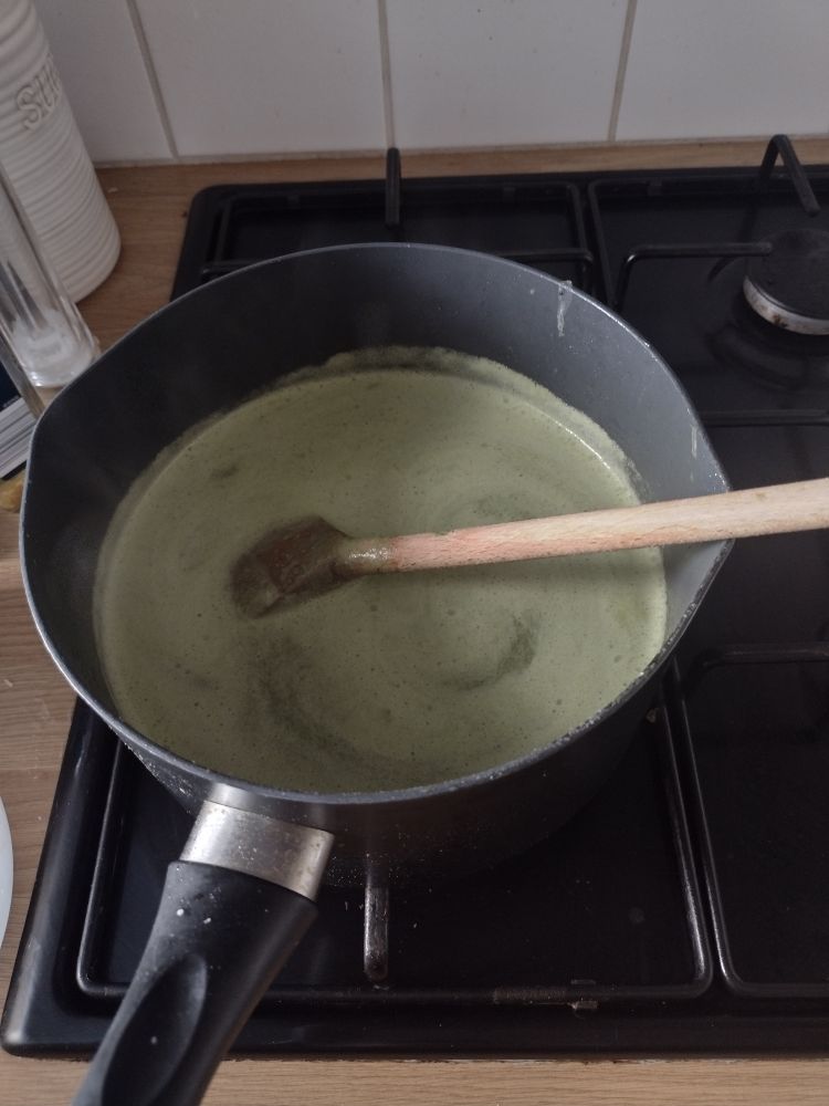 A colour image of a saucepan on a hob with a healthy lunch: leek, green bean and spinach soup. 