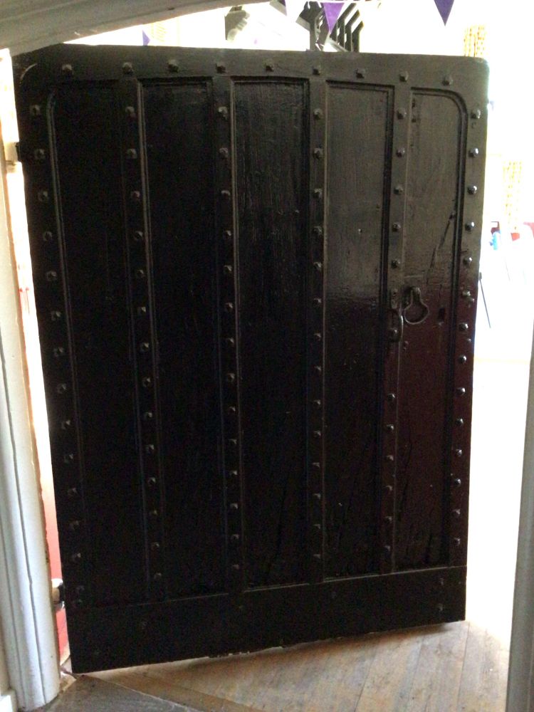 Colour image of a 17th century wooden door. Probably oak, it used to be the exterior door of the hall. Almost square in shape with ironwork in good condition.
