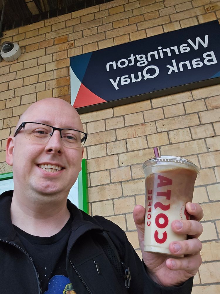 Me at a train station with a chilled coffee. 