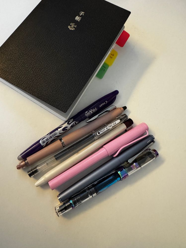 a collection of my pens. This is a list of the pens:
2 times a Pilot Frixxion pen
1 Pilot G-tec pen
1 Pilot Ilmily pen
1 Lamy safari rollerball pen
1 Lamy Studio fountain pen
1 TWSBI 580 Diamond Iris fountain pen
