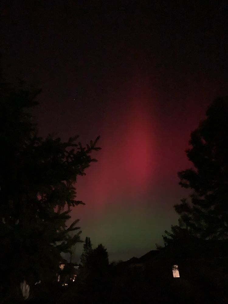 A photo of the red and green Aurora borealis against a night sky