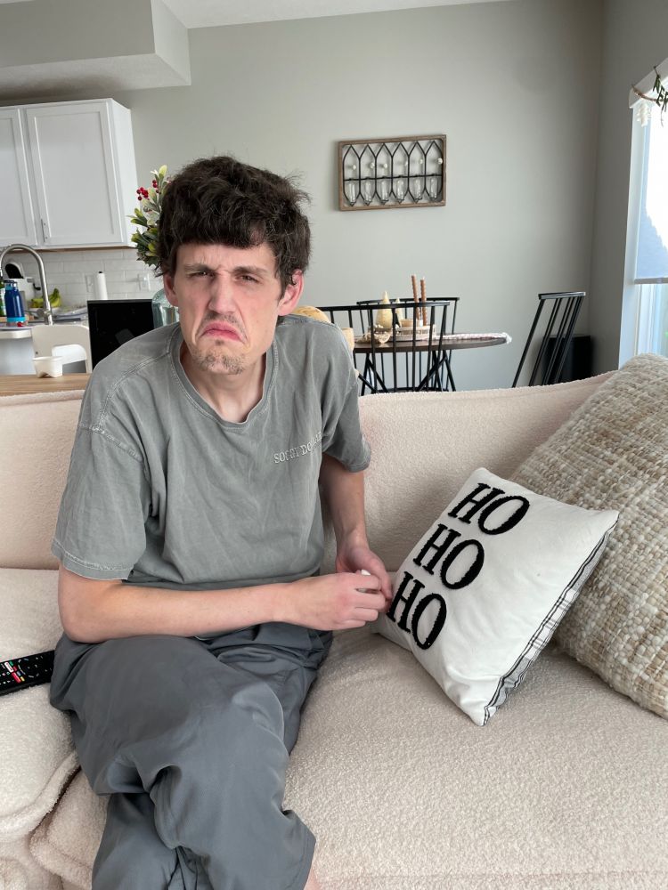 A man sitting on the couch, scowling cartoonishly at the camera. 