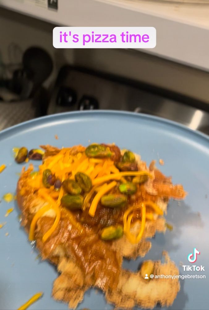 A very gross looking concoction of crushed bread, drowned in salsa, cheese and unshelled pistachios. The caption reads “it’s pizza time”