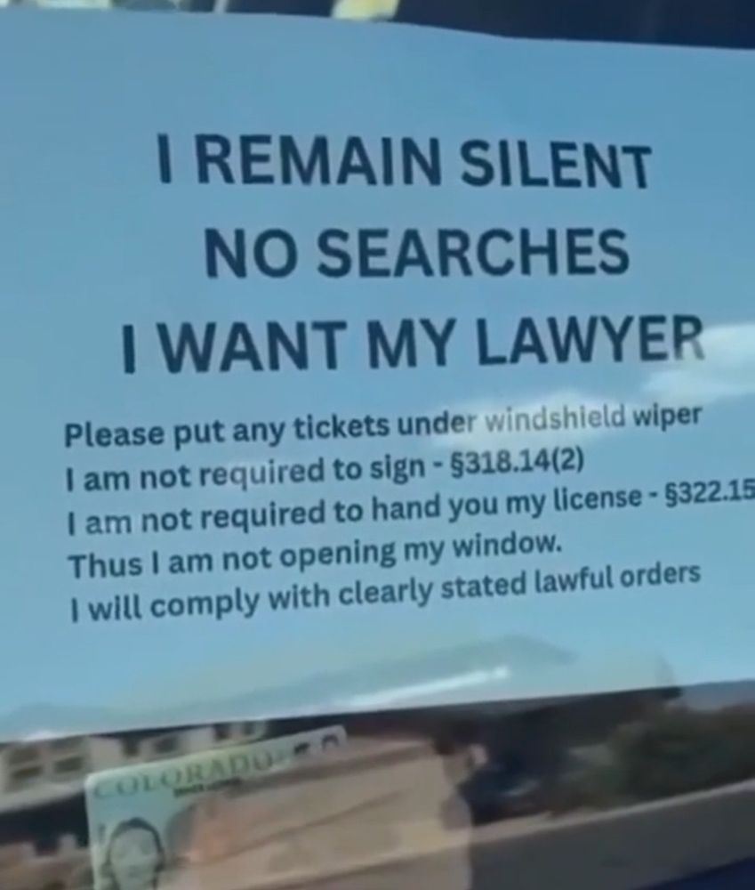 Colorado woman stopped by a cop hold up her driver's license and a sheet of paper to her closed car window

The paper:
I remain silent
No searches
I want my lawyer
Please put any tickets under my windshield wiper
I am not required to sign - 318.14(2)
I am not required to hand you my license 322.15
Thus I am not opening my window
I will comply with clearly stated lawful orders