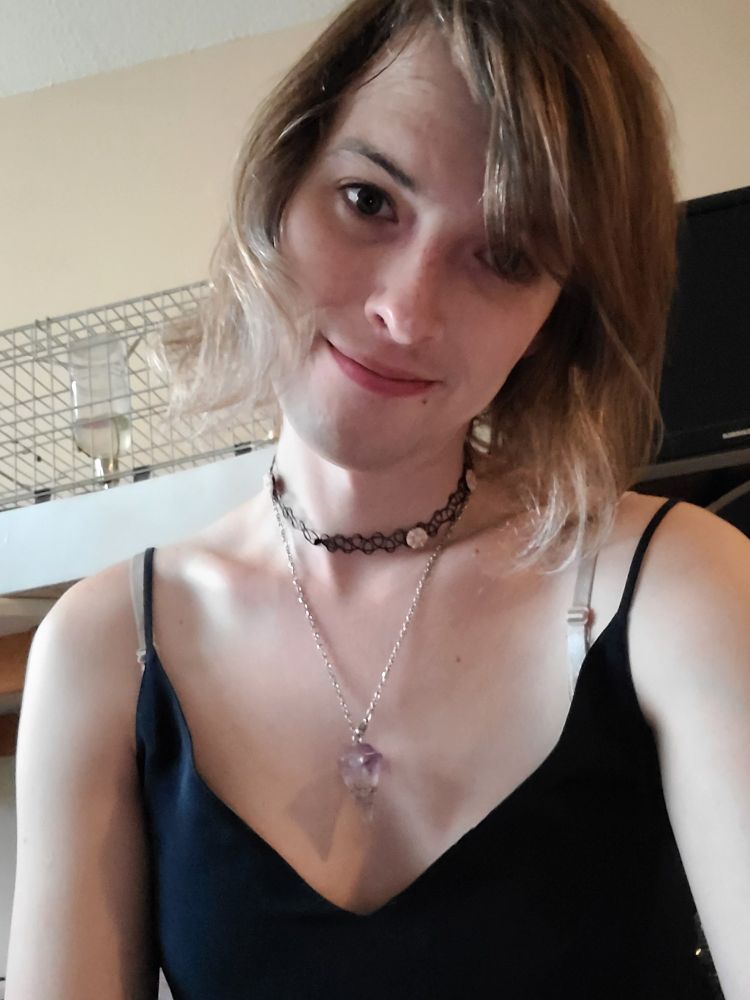 A smiling Cinderfey System with a quartz pendent hanging from her neck as she smiles into the camera.