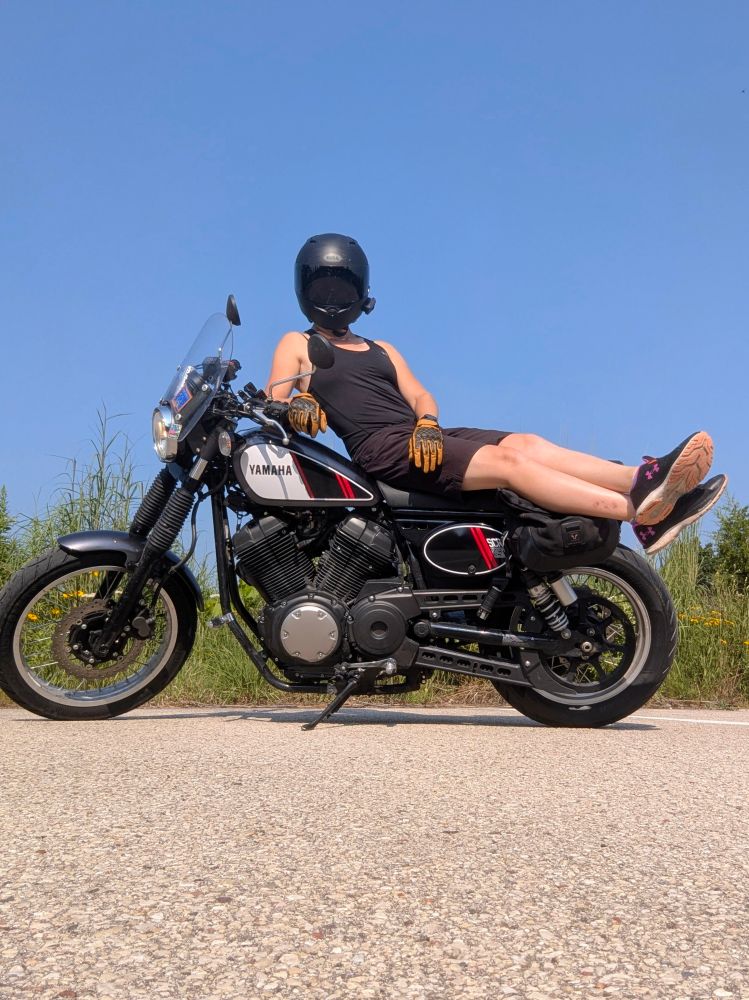 girl in a tank top stretched out on a motorcycle 