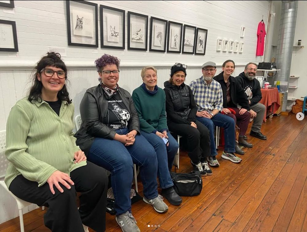 Our artist panel on Dec 15, photo by Buttered Roll. The seven artists in the show sit in front of a wall of drawings by Bill Rood