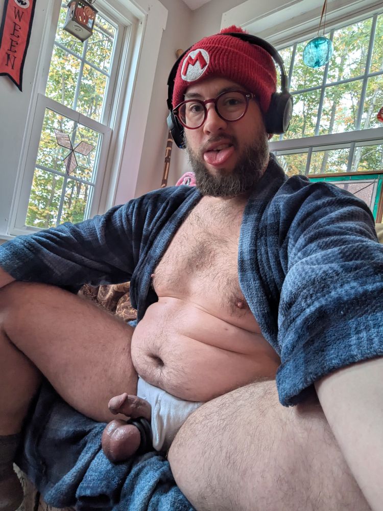 Baphobator sitting in a sunny room, robe open exposing his genitals that are pulled through the fly of his white briefs.