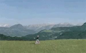 a woman in a long dress is standing in a field with mountains in the background .