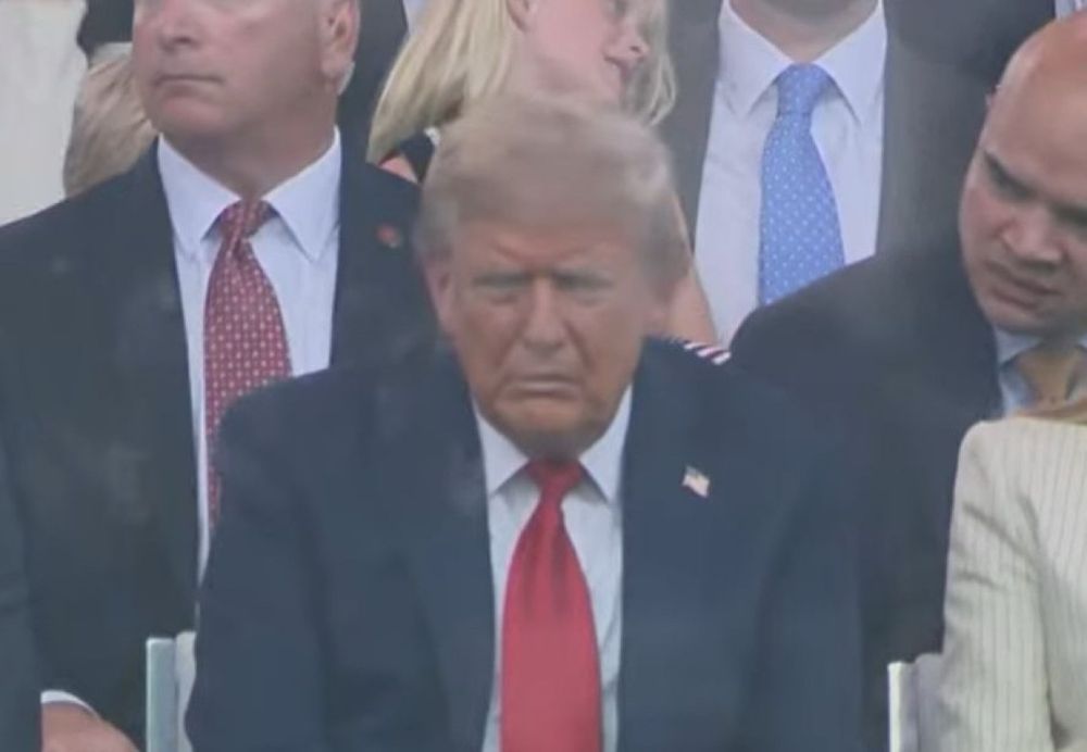 Donald Trump, in a navy blue suit and red tie, looking dejected at his military parade