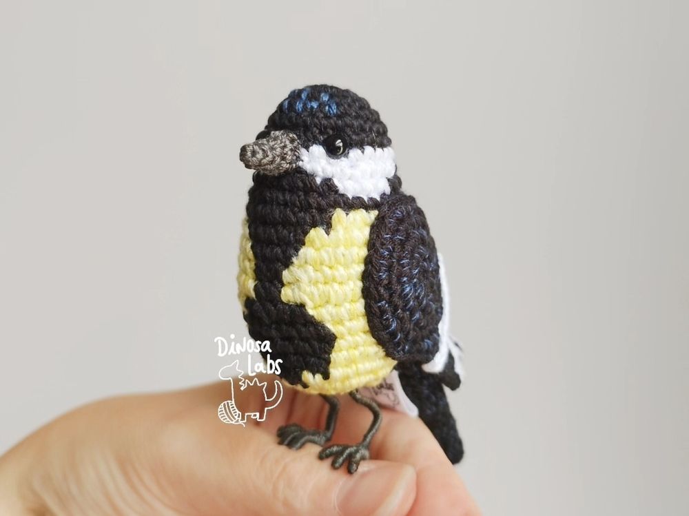 Amigurumi de un carbonero común (ave). Posado con sus patitas en mis dedos.