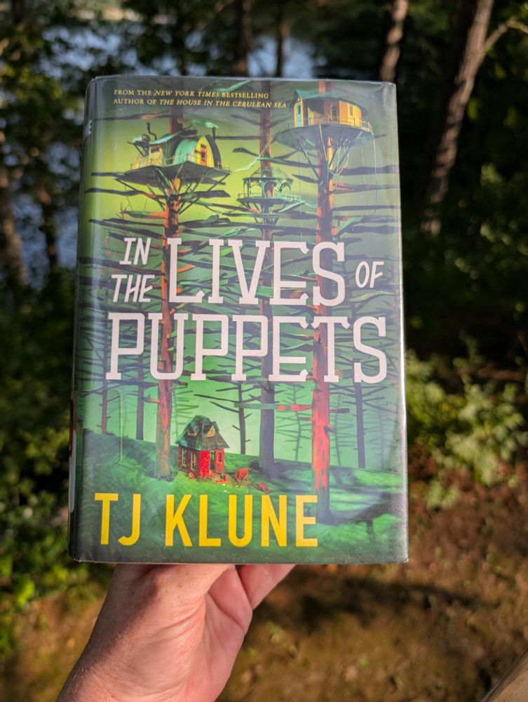 The cover of author TJ Klune's novel 'In the Lives of Puppets' which shows a small red brick house on a forest floor, with elaborate treehouses built high above. It called to me as I browsed an aisle in the library looking for a different book (Miéville's The City & The City, which I haven't been able to start yet bc I am still processing this one, a day after finishing it). I did the flip-open-skim there in the library aisle and was immediately swept away. Beautiful, just beautiful.
