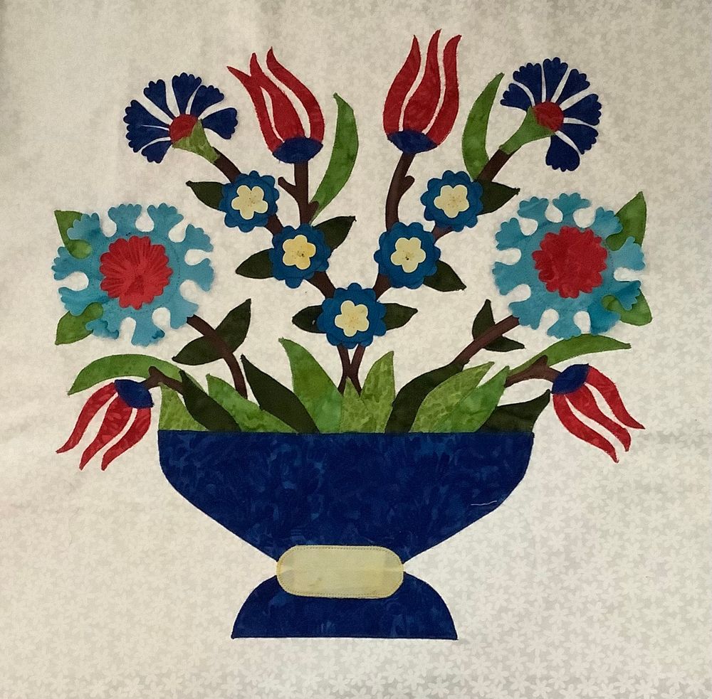 Block 4 white background, red and blue flowers in a blue vase. Pattern by Tamsin Harvey called Iznik Gardern