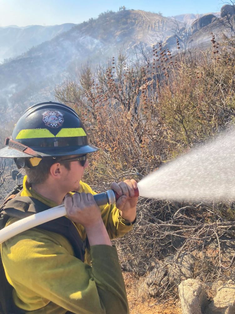 Yurok firefighter Jasper Hostler sprays water on Hughes Fire.