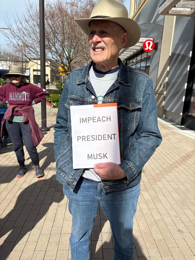 Protester holding a sign that reads “IMPEACH PRESIDENT MUSK”
