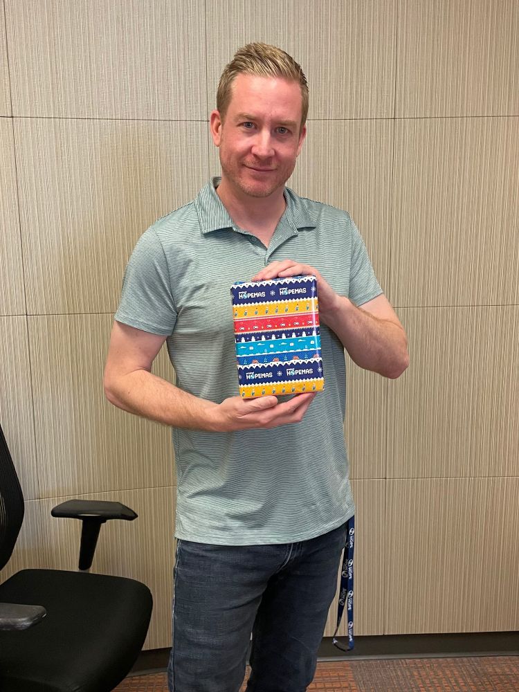 Evan holding a wrapped DIY kit in colorful patterned Hopemas wrapping paper.