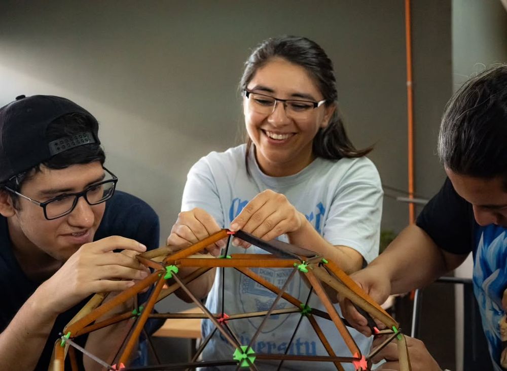 Tres personas arman un domo geodésico de madera