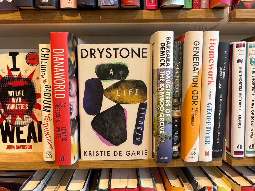 Hardback copy of the book "Drystone: A Life Rebuilt" by Kristie De Garis, seen on the shelf in a bookshop. 

It is turned with the cover facing outwards, occupying a prominent space on the shelf. Most of the other books on the shelf have the spine facing out and are less immediately obvious.