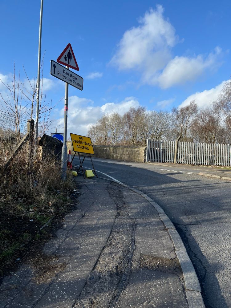 Road with a warning sign to beware of pedestrians, and a sign that points to “Dawsholm Recycling Centre”

Below these signs is a temporary yellow roadworks sign that reads “NO PEDESTRIAN ACCESS”

It is a sunny winter day with blue skies and white fluffy clouds 