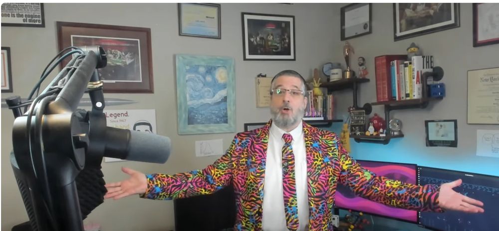 Leon wearing a vibrant, day-glo color, tiger-pattern suit (tie, jacket, and pants) that looks like something out of a Lisa Frank picture.