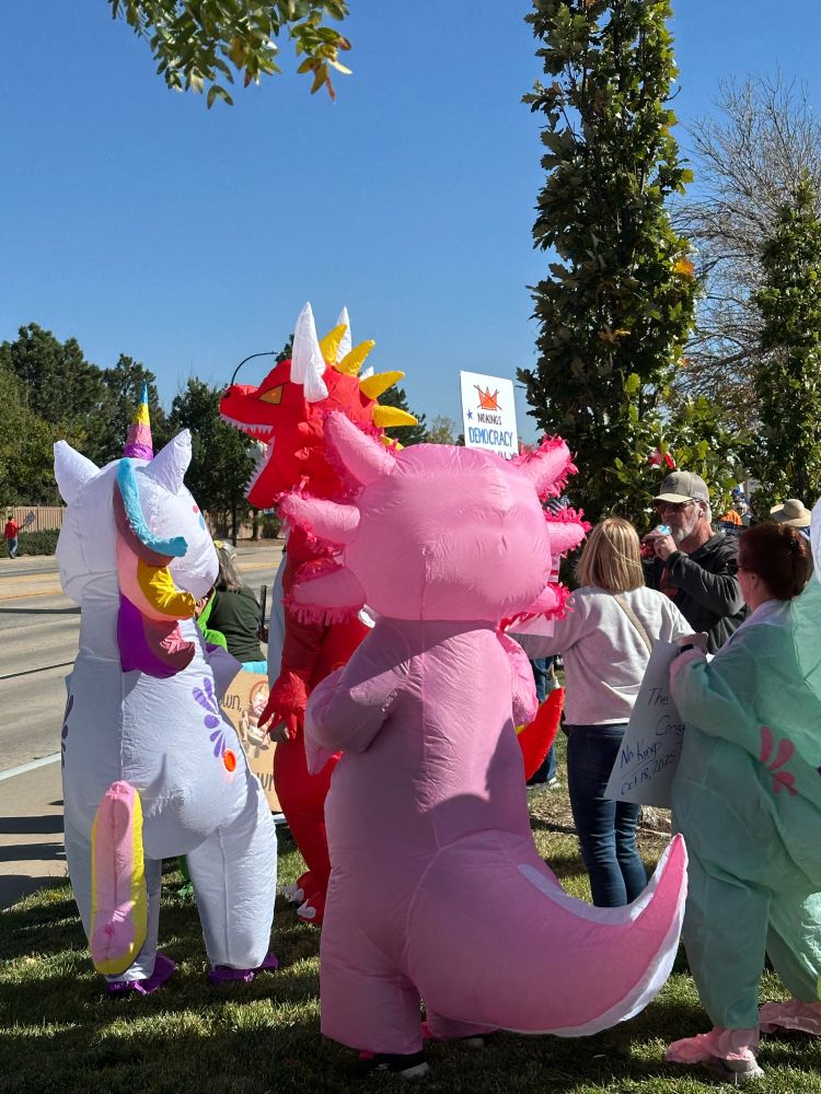 Two costumed protestors dressed as Rainbow Dinosaurs