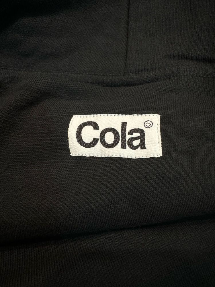 Clothing tag sewn onto back of hoodie neck with Cola logo in black 