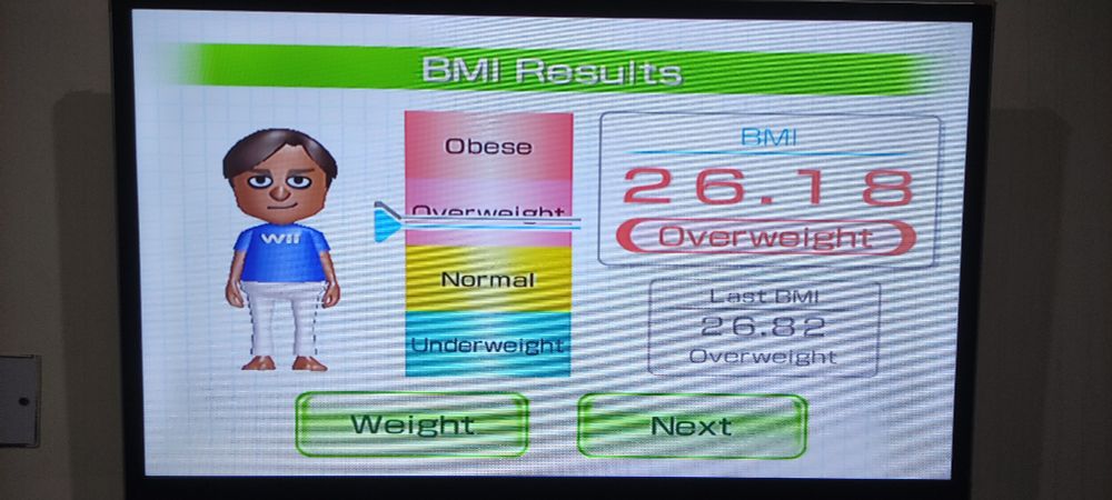 A tv screen with an Avatar standing on the left, a label saying 26.18 BMI on the right and a scale in the middle with a bar on a label that says "overweight"