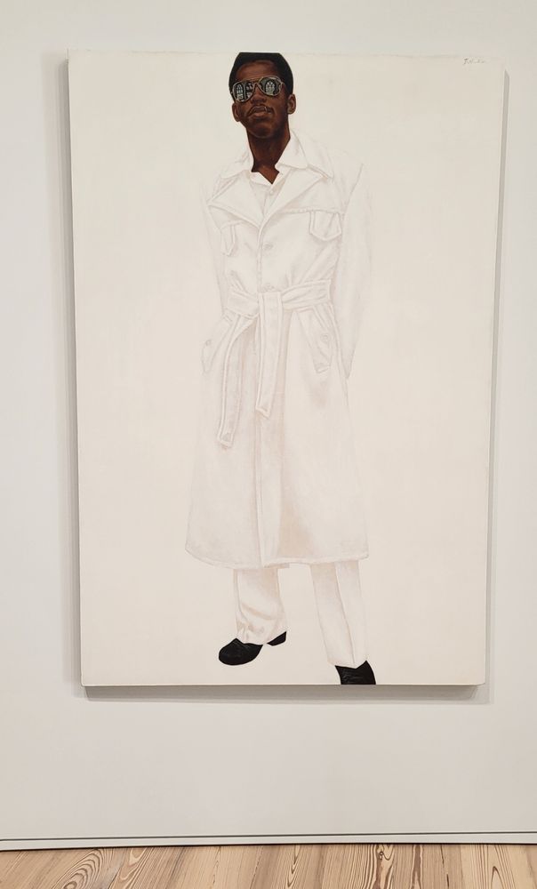 Painting of a young Black man with brown skin, a short neat afro, and reflective sunglasses wearing a long white trench coat, tailored white trousers, and Black shoes on a white background. 
Elegant and attractive Black people in white-on-white is a Hendricks trademark.