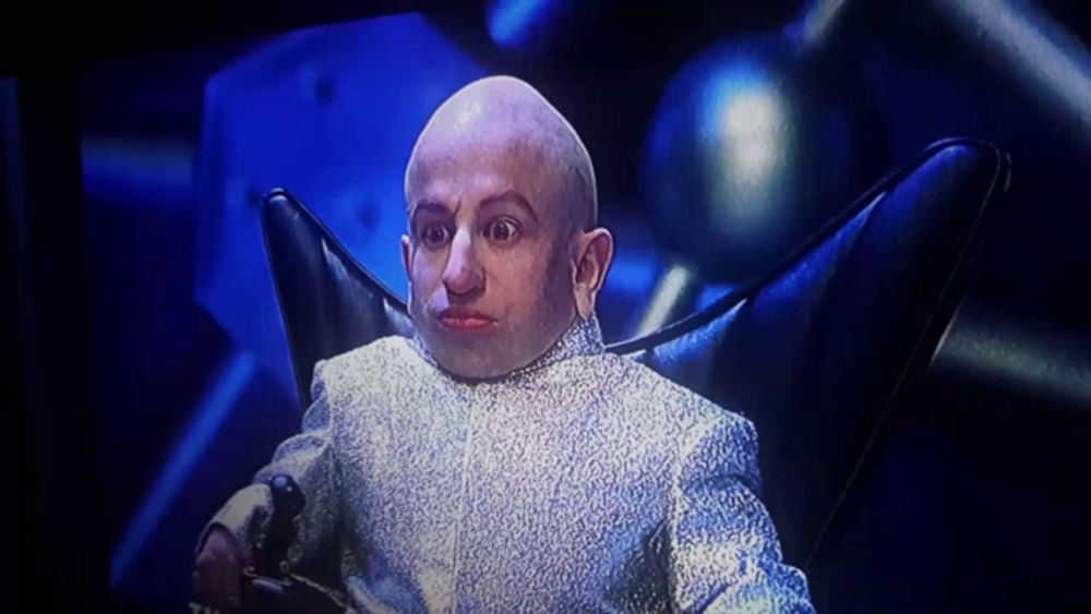 a bald man is sitting in a chair with a microphone in front of him