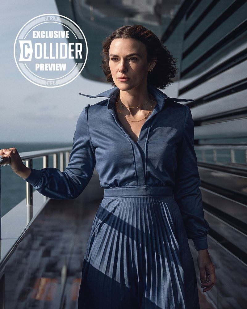 Keira Knightley in a blue-gray kinda Star Warsy sleeved dress with an open, flared collar. She's on the side deck of a large ship, staring intently at something unseen in the water. She is radiant.