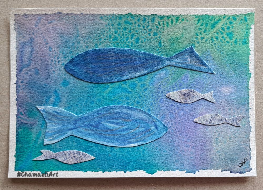 Eine abstrakte Collage mit Aquarellfarben im Querformat, in Postkartengröße: Der Hintergrund besteht aus blauen, grünen und violetten ineinander fließenden, melierten Farben, zum Teil mit Blasenstruktur. Zwei große blaue sowie drei kleine blaugraue, fischartige, ausgeschnittene Silhouetten wurden auf dem Hintergrund aufgeklebt. Das Bild hat einen weißen, unregelmäßigen Rand. Künstlerinmonogram unten rechts. 