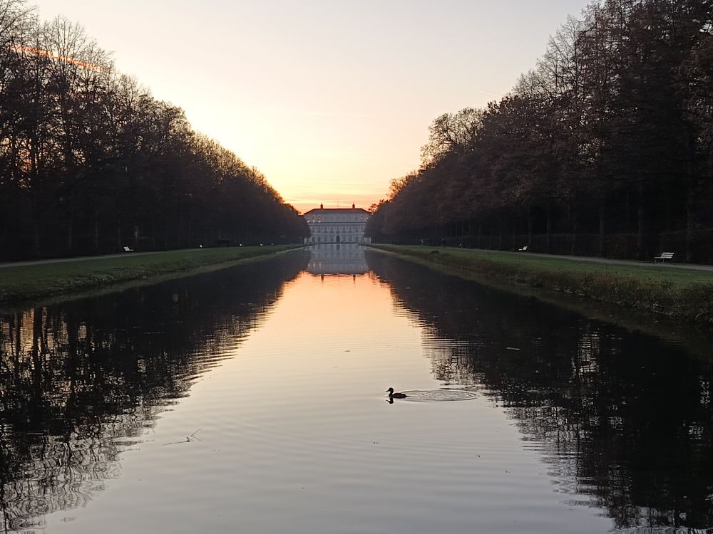 Castle Schleißheime during sunset, showing the reflection of the building on the water surface 