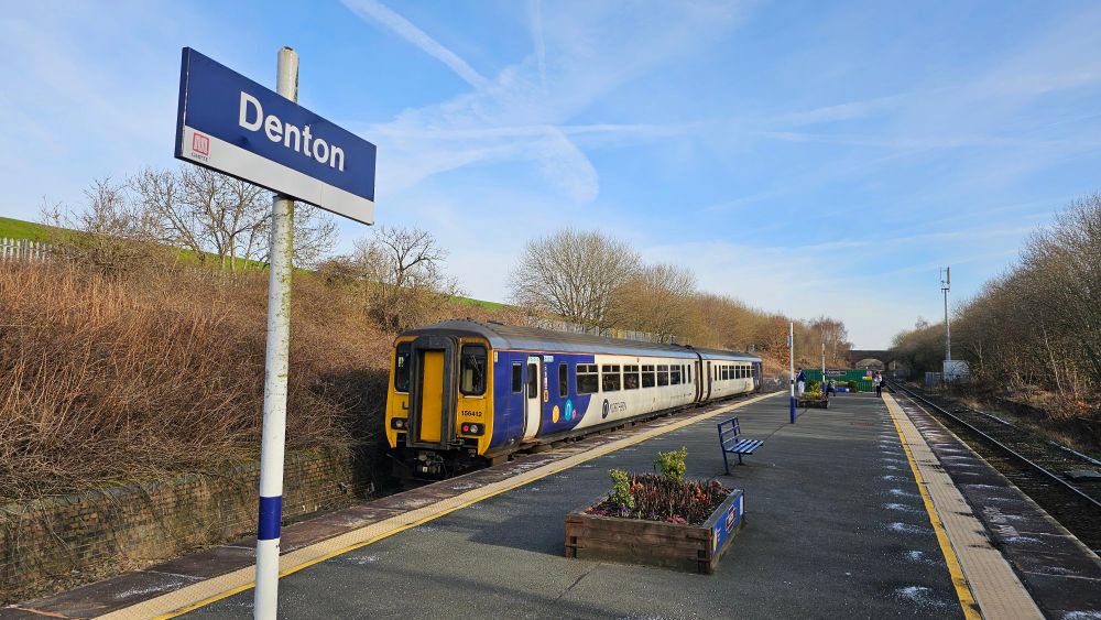 A Northern Class 156 departs Denton station in bright winter sunshine