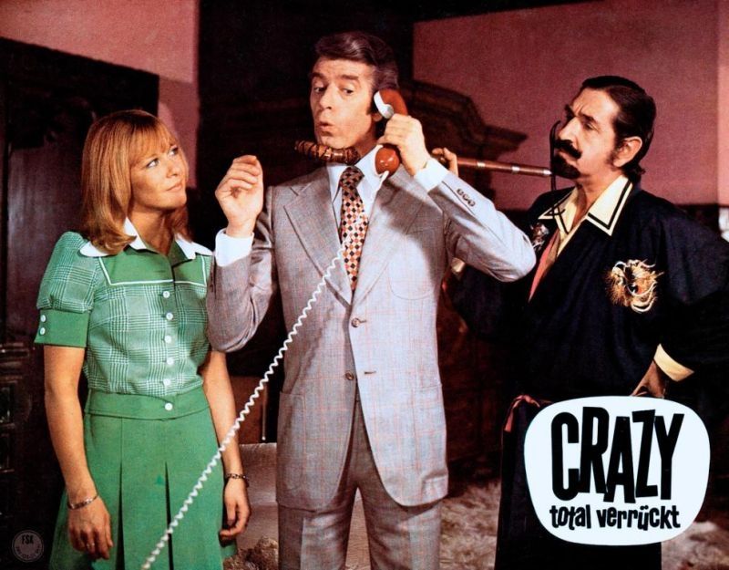 Foto zeigt ein Plakat der deutschen Filmkomödie "Crazy - total verrückt" mit den Darsteller:innen Monika Lundi, Rudi Carrell und Don Jaime de Mora y Aragón.