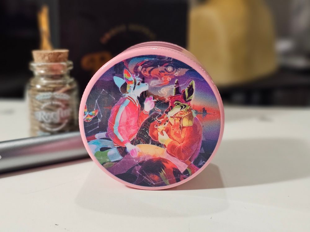 Pink ceramic coated grinder with a printed graphic featuring two characters smoking 