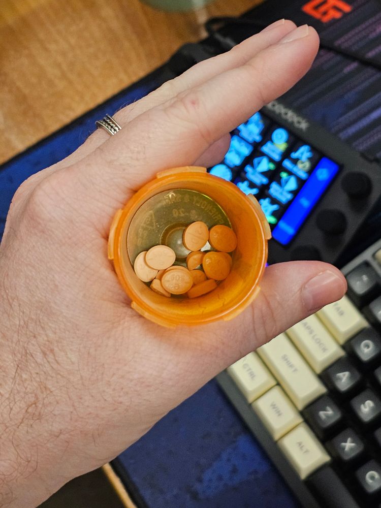 A photo of a hand holding an open bottle of Adderall 