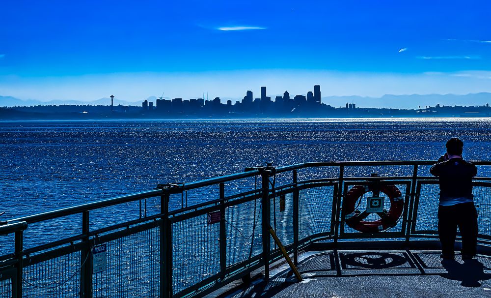 View of Seattle from the deck of the ferry, with a little boy taking a picture in the foreground 
