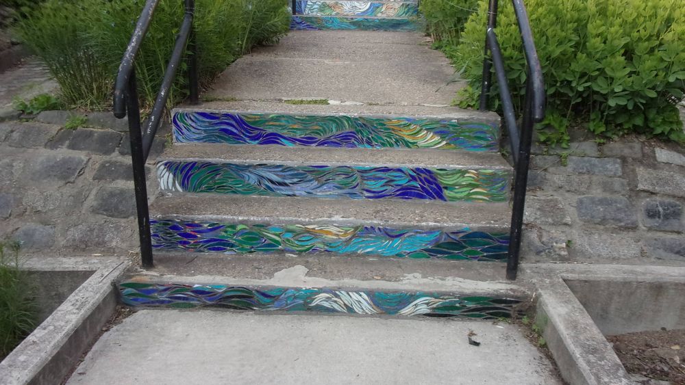Painted Fountain Street steps with railings in center. Bushes on side.