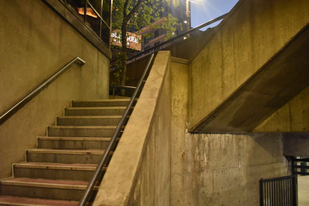 Stairs that lead to Septa concourse. Broad and Locust streets, Stairs, wall, and hand rails on left and center of picture. Upper stairs at top of right, gate and wall on bottom right.