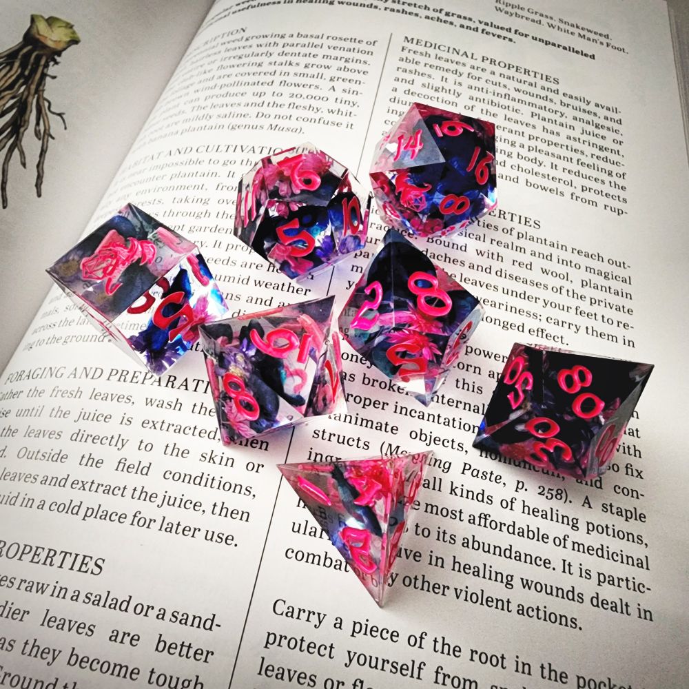 A clear DnD dice set with flowers inside on top of a page of a book